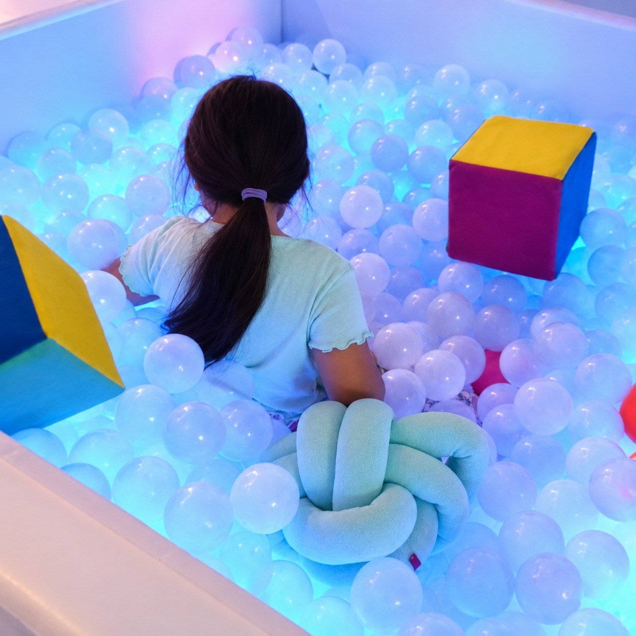 Niña realizando exploración táctil y propioceptiva en alberca de pelotas sensorial
